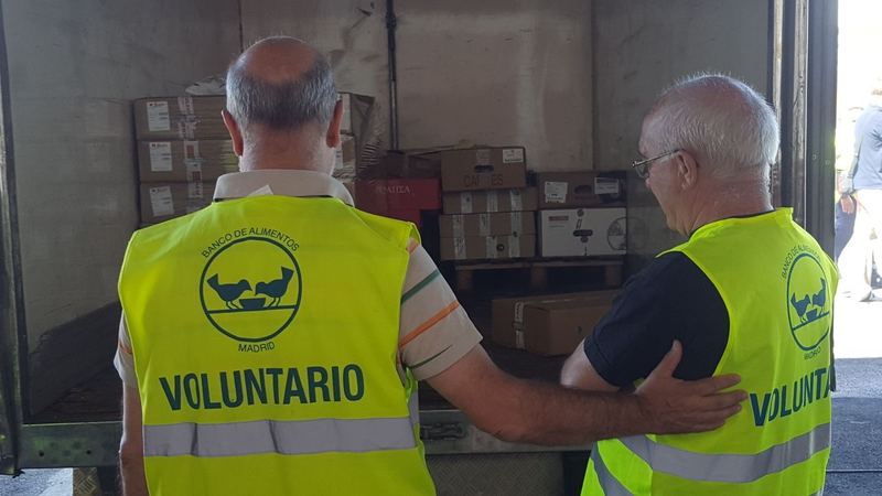 Dos voluntarios con chaleco amarillo en el almacén de un banco de alimentos