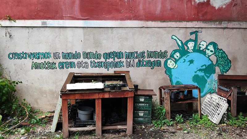 Mesa con plantones junto a un mural en un huerto comunitario de Pamplona