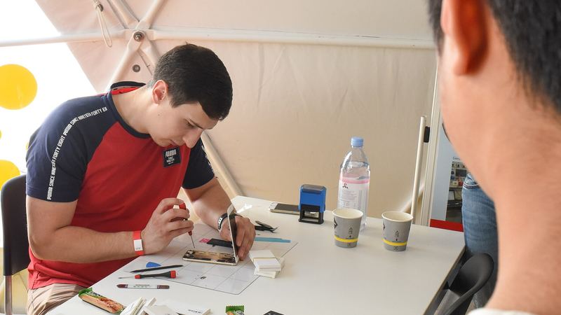 Un joven repara un aparato con un destornillador en un taller de reparación