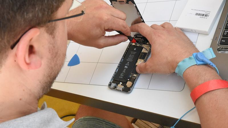 Manos reparando un teléfono móvil abierto